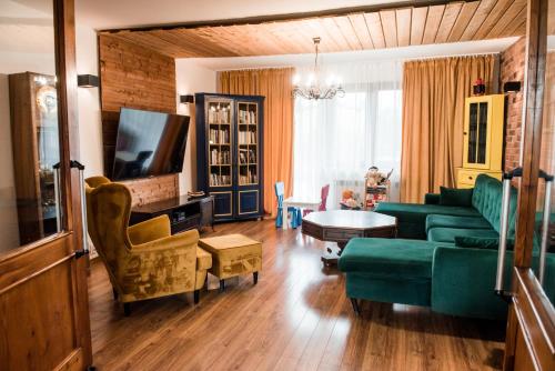 uma sala de estar com um sofá verde e uma televisão em Projekt 44 Apartament em Oświecim