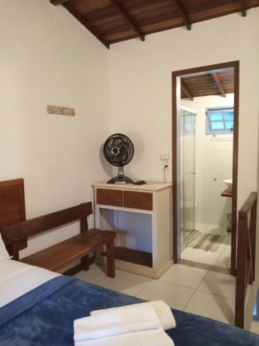 a bedroom with a bed and a desk with a fan at Pitanga Ilha Grande in Abraão