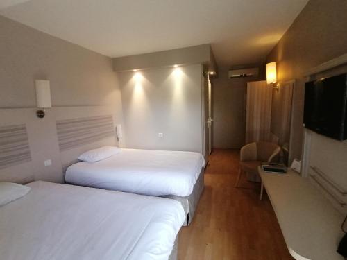 a hotel room with two beds and a flat screen tv at Kyriad Toulouse Sud - Roques in Roques Sur Garonne