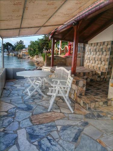 a patio with a table and chairs on a stone floor at To Kyma in Skala Kallirakhis