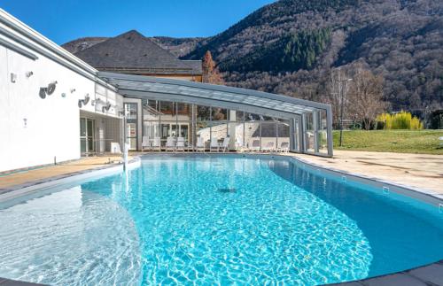 une grande piscine devant une maison dans l'établissement Village Club Les Balcons des Pyrénées, à Saint-Mamet