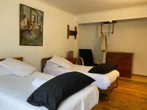 a bedroom with three beds and a painting on the wall at El Pillan "Travelers" House in Santiago