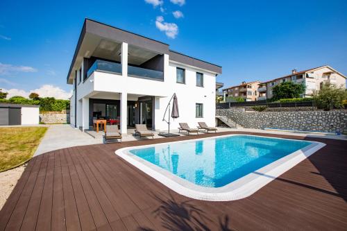 a house with a swimming pool in front of it at Apartments Aqua in Malinska