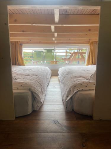 two beds in a room with a window at Tiny house du Château du Boulay-Morin in Le Boulay-Morin
