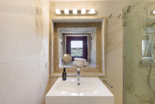 La salle de bains est pourvue d'un lavabo et d'un miroir. dans l'établissement Casa do Outeiro, à Guilhabreu