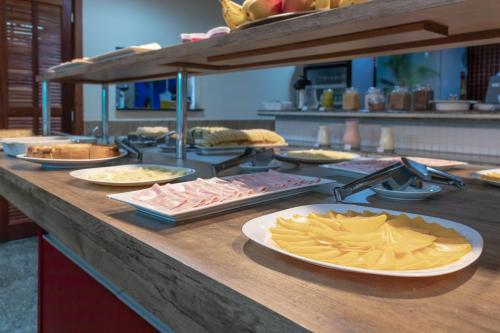a buffet with plates of food on a counter at Mediterrane Hotel by Castelo Itaipava in Arraial do Cabo