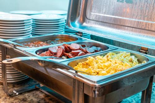a buffet with a tray of food on a table at Mediterrane Hotel by Castelo Itaipava in Arraial do Cabo