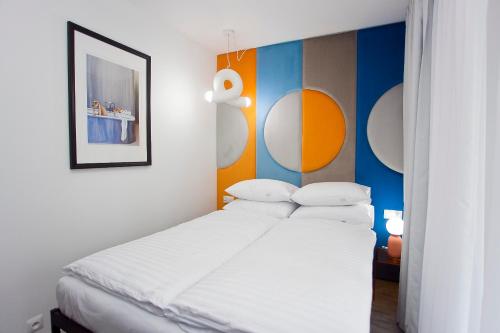 a bedroom with a bed with white sheets and colorful walls at Willowa NO. 5 APARTAMENTS in Wisła