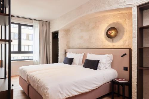 een slaapkamer met een groot bed met witte lakens bij Rosa Hotel in Oostende