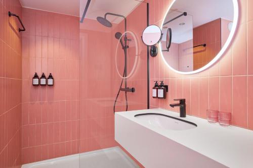 ein rosafarbenes Bad mit einem Waschbecken und einem Spiegel in der Unterkunft Rosa Hotel in Ostende