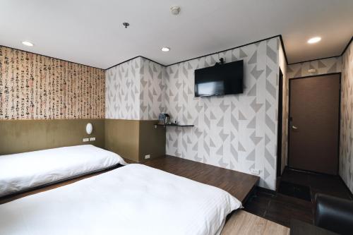 a bedroom with two beds and a flat screen tv at Sofu Hotel in Taipei