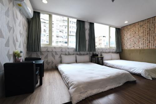 um quarto com 2 camas, uma secretária e janelas em Sofu Hotel em Taipei