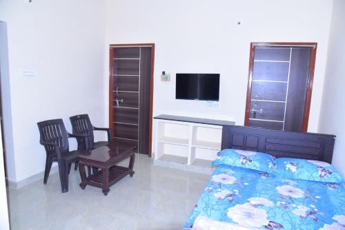 um quarto com uma cama e cadeiras e uma secretária em ANAND NIVAS em Tirupati