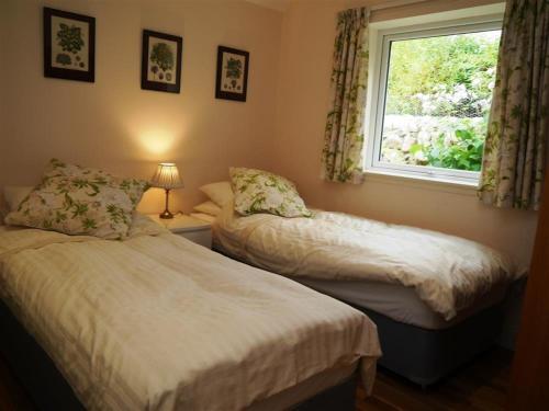 deux lits dans une chambre avec une fenêtre dans l'établissement Seabank Cottage, à Rockcliffe