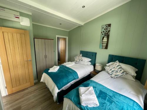 ペンブルックシャーにあるCanaston Waterside Lodgesのベッドルーム1室(青と白のベッド2台付)