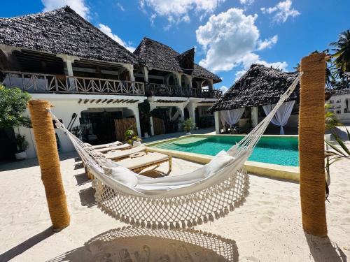 a hammock in front of a house with a swimming pool at Olamanga Beach Villa Adults Only in Jambiani