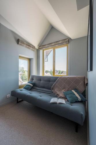 a large blue couch in a room with windows at Palanga Visit Apartments and SPA in Palanga