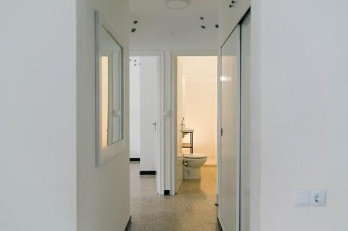 Baño blanco con aseo y espejo en Apartaments Falcó, en Llançà