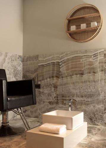 a bathroom with a sink and a chair at Paralos Venus Suites Adults Only in Hersonissos