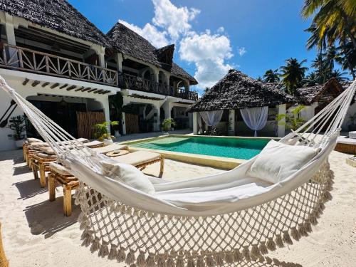 une villa avec un hamac et une piscine dans l'établissement Olamanga Beach Villa, à Jambiani
