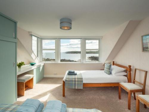 a bedroom with a bed and two windows at Neptune Cottage in Rockcliffe