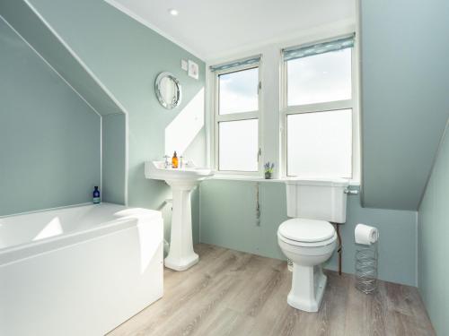 La salle de bains est pourvue de toilettes blanches et d'un lavabo. dans l'établissement Neptune Cottage, à Rockcliffe