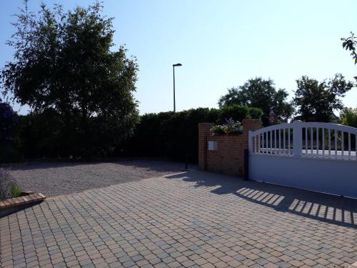 a driveway with a white fence and a brick wall at Thérouanne en Berry in Plaimpied-Givaudins