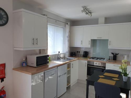 a kitchen with white cabinets and a table with a microwave at Modern, self-contained annexe in the countryside in Callington