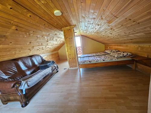 um quarto com um sofá e uma cama num sótão em zidanica Bunderšek em Šentjanž