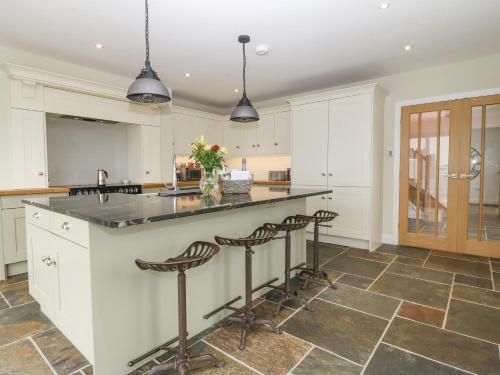 a kitchen with white cabinets and a large island with bar stools at Bryn Tirion in Holyhead
