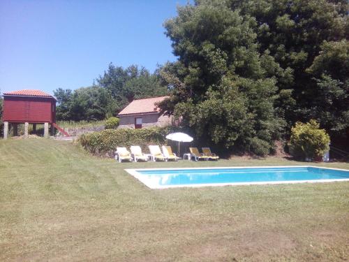 einen Pool in einem Garten mit Stühlen und einem Sonnenschirm in der Unterkunft Quinta da Fonte Arcada in Paço de Sousa