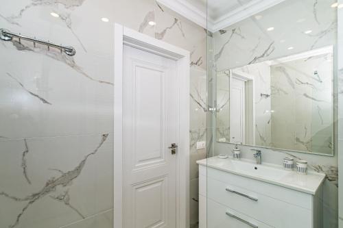 a white bathroom with a sink and a mirror at Premium Apartment Chisinau in Chişinău