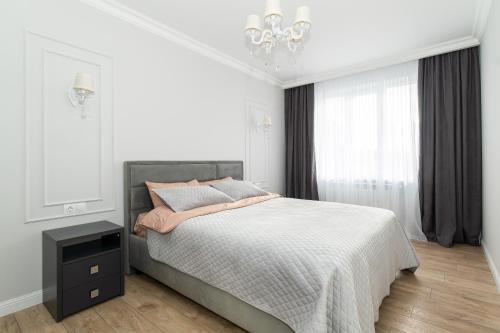 a white bedroom with a bed and a chandelier at Premium Apartment Chisinau in Chişinău