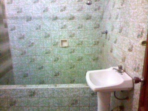 baño con lavabo blanco y pared de azulejos verdes en Alquilo 3 cuartos, 2 baños, patio, cocina, sala. Comas, en Lima