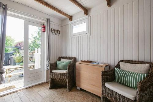Zimmer mit 2 Stühlen und einer Tür zur Veranda in der Unterkunft In Ons Tuintje - aan zee - Callantsoog in Callantsoog