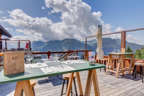 a table on a deck with a view of mountains at ILY Hotels & Spa La Rosiere in La Rosière