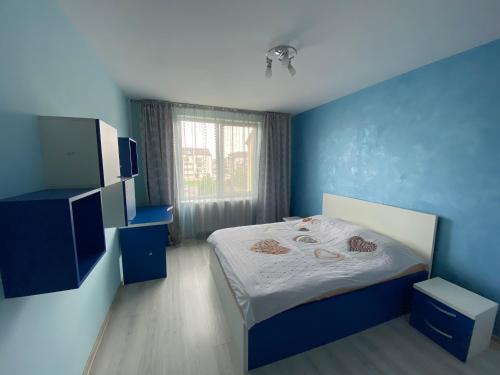 a blue bedroom with a bed and a window at Sofia Apartments in Floreşti