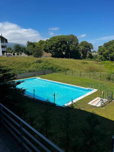 een groot zwembad in een veld met een hek bij Apartamento ideal en urbanización con piscina in poo de Llanes