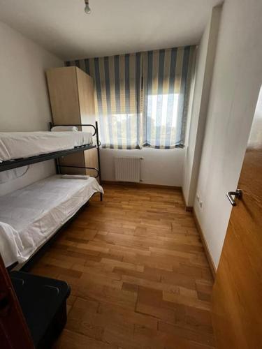 een kleine kamer met 2 stapelbedden en een raam bij Apartamento ideal en urbanización con piscina in poo de Llanes