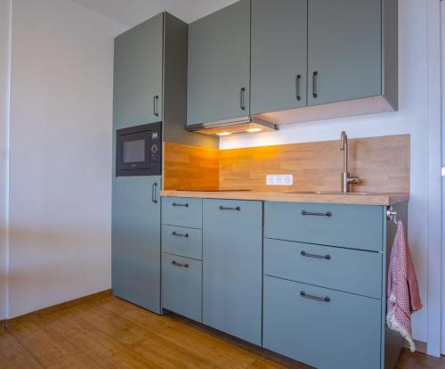 eine Küche mit blauen Schränken und einem Waschbecken in der Unterkunft Cosy and modern studio with view - Huez - Welkeys in Huez