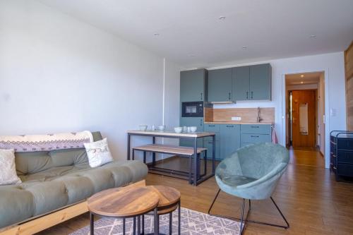 ein Wohnzimmer mit einem Sofa und einer Küche in der Unterkunft Cosy and modern studio with view - Huez - Welkeys in Huez