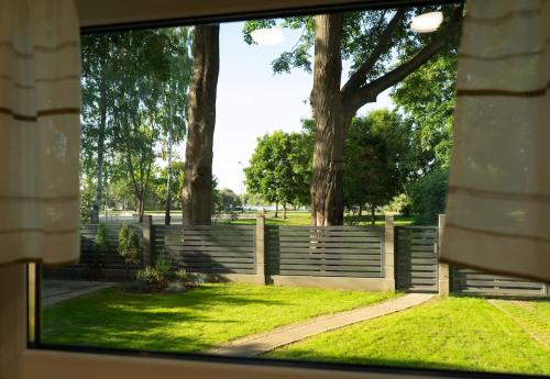 a fence in a park with trees and grass at Oak Heart, Lucavsalas namiņš in Rīga