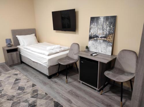 a bedroom with a bed and two chairs and a desk at Villa Grácia in Badacsonytomaj