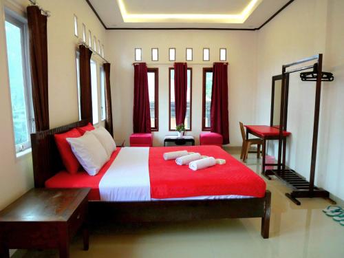 een slaapkamer met een rood en wit bed en 2 handdoeken bij The Sanduk Homestay in Rantepao