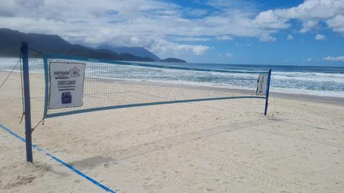 a volleyball net on a beach with the ocean at Pousada North Shore Maresias - 2 quadras da praia - Casas de 2 quartos - 80 m2 -2 banheiros -piscina sauna - estacion-churrasq privativa -wifi animais de peq porte roupa de cama e banho in Maresias
