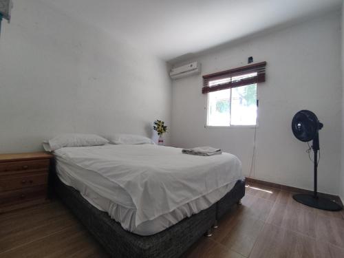a bedroom with a bed and a fan and a window at Finca Mar de Leva in Santa Marta