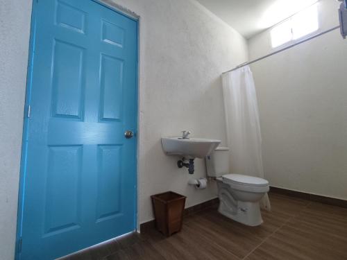 uma casa de banho com uma porta azul e um WC e lavatório. em Finca Mar de Leva em Santa Marta