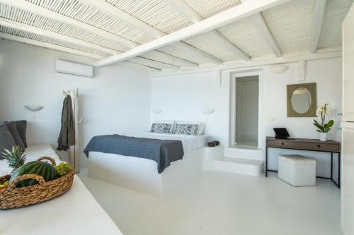 ein weißes Schlafzimmer mit einem Bett und einem Tisch in der Unterkunft Villa Ruby by Mykonos Rocks in Mykonos Stadt