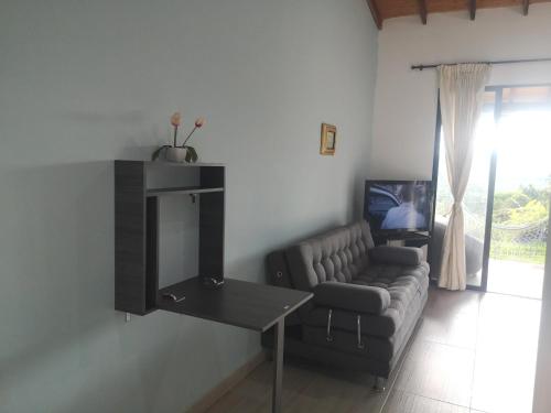 a living room with a couch and a table and a tv at Villa Namaste, Cabaña Namaste 1 in Curití