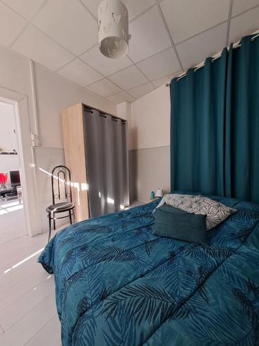 - une chambre avec un lit doté de draps bleus et d'une chaise dans l'établissement Appartement cosy sur Masevaux, à Masevaux